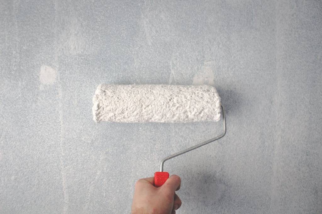 Paint roller applying paint to an exterior wall
