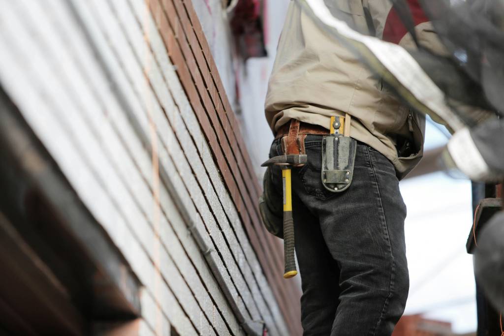 Siding installer with tool belt working on an exterior wall